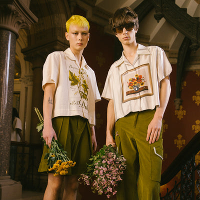 Two people in S.S.Daley clothes while holding floral arrangements. 